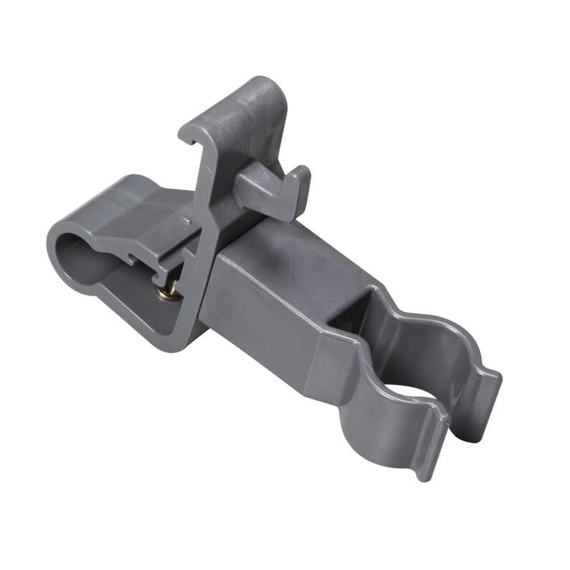 The TASKI accessory holder from Diversey Deutschland GmbH & Co. OHG is a gray plastic clip with two round openings and a locking hinge. It is used for securely fastening cylindrical cleaning tools and organizing cleaning accessories. Smooth surface, angled details.