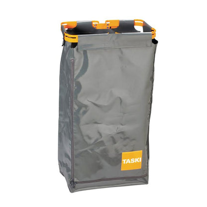 The TASKI oversack for garbage bags from Diversey Deutschland GmbH & Co. OHG is a gray, rectangular bag with a side zipper, orange carrying handles, and the word "TASKI" on a yellow square - ideal for hygienic waste disposal.
