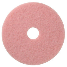 The pink, round TASKI Americo Remover Pad Kombipad for cleaning and polishing from Diversey Deutschland GmbH & Co. OHG has a rough texture and a hole in the middle, viewed from above on a white background.