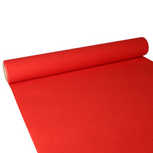 A partially unrolled PAPSTAR table runner, Tissue “ROYAL Collection” (3 m x 40 cm) from PAPSTAR GmbH shows its structured red surface and the cylindrical cardboard core as it extends over a flat surface.