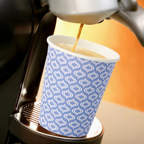A Starpak 20 drinking cup "To Go" made of recyclable cardboard (0.2 l, Ø 8-9.1 cm) with a blue-white pattern stands under the spout of a coffee machine pouring fresh coffee. The scene is hellishly lit.
