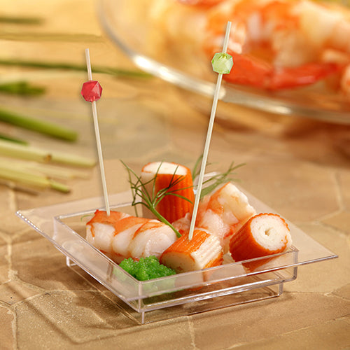 A small transparent, square dish contains imitation crab and shrimp, two colorful PAPSTAR 100 Fingerfood - Picks from PAPSTAR GmbH made of bamboo, garnished with green herbs and a small portion of green roe.