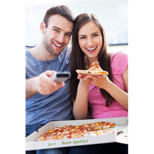 A smiling couple sits closely cuddled on a sofa, in front of them lies an open PAPSTAR 100 pizza boxes, cellulose "pure" rectangular by PAPSTAR GmbH. The man holds the remote control, the woman a slice of pizza – both enjoy their eco-friendly dinner.