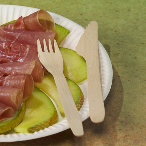 A paper plate from PAPSTAR GmbH with green apple slices and rolled cured meat is topped with PAPSTAR forks made of FSC® wood "pure", 16.5 cm, environmentally friendly. The plate is on a green base.