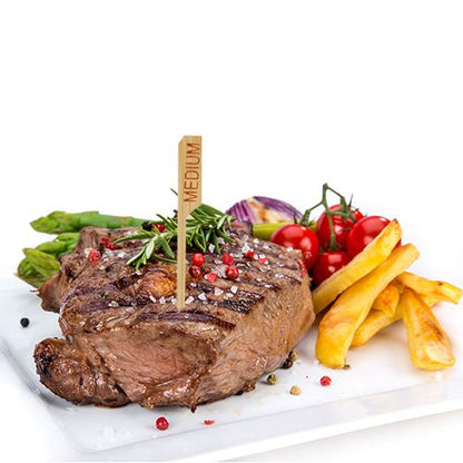 A grilled steak labeled "medium" with the PAPSTAR 250 steak marker 9 cm from PAPSTAR GmbH is served on a white plate with French fries, asparagus, cherry tomatoes, red onions, and herbs – perfect for the professional restaurant kitchen.