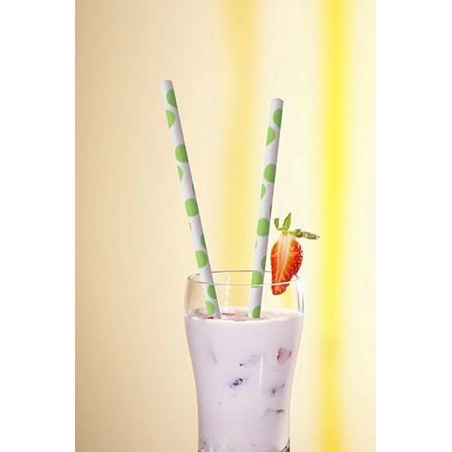 A glass with a creamy white drink and fruit pieces is topped with two PAPSTAR 100 straws, paper Ø 6 mm from PAPSTAR GmbH, with green dots and a strawberry slice on the rim, against a bright yellow background.