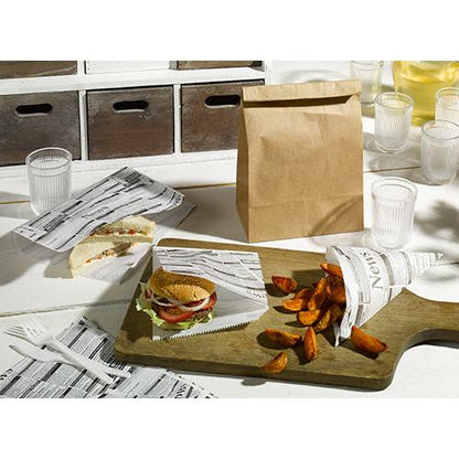 Ein Tisch mit einem Sandwich, einem Burger und Kartoffelecken, eingewickelt in PAPSTAR 5 Einschlagpapiere 3 cm x 2 cm „Newsprint“ von der PAPSTAR GmbH, daneben eine braune Papiertüte, Plastikbecher und -besteck sowie ein hölzernes Servierbrett auf einer weißen Oberfläche.