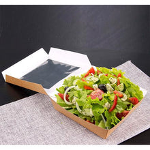 Eine PAPSTAR 25 Feinkostbox aus Pappe mit PLA-Sichtfenster von PAPSTAR GmbH präsentiert frischen Salat mit Gemüse und Dressing, arrangiert auf einem grauen, geflochtenen Tischset vor dunklem Hintergrund.