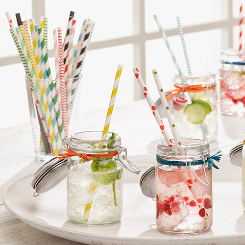 Several glasses with ice, fruit, and drinks are placed on a white tray, each equipped with PAPSTAR 100 paper straws (Ø 6 mm) from PAPSTAR GmbH. Additional glasses in the background also feature the sustainable, patterned paper straws.