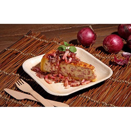 A piece of Spanish omelet with red onions is served on a square “Pure” plate from PAPSTAR GmbH from the PAPSTAR 6-piece set, accompanied by bamboo knife and fork. In the background, red onions with skin can be seen on a woven mat.