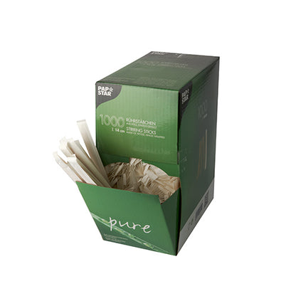 In a green box from PAPSTAR GmbH with the inscription "1000 wooden stir sticks, "pure", individually wrapped" numerous wooden stir sticks protrude from the open top against a white background.