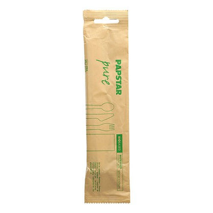 A sealed brown paper package from PAPSTAR GmbH labeled "pure" contains the environmentally friendly PAPSTAR cutlery set wood: knife, fork, spoon, and paper napkin. Green pictograms/text on the packaging indicate the environmentally friendly cutlery set.