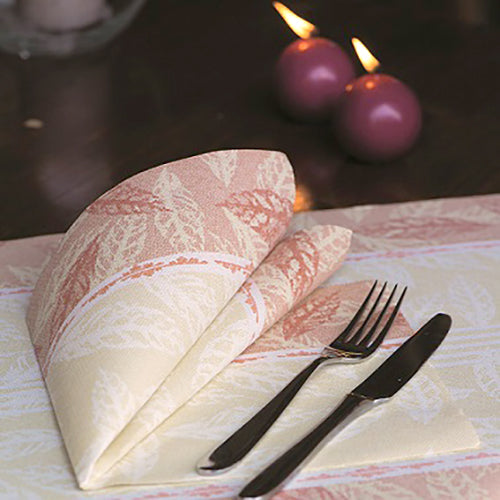 Eine gefaltete rote Serviette PAPSTAR 50 Servietten "ROYAL Collection" 1/4-Falz 40 x 40 cm von PAPSTAR GmbH liegt neben Gabel und Messer auf einem gedeckten Tisch. Im Hintergrund sind zwei brennende violette Kerzen zu sehen.