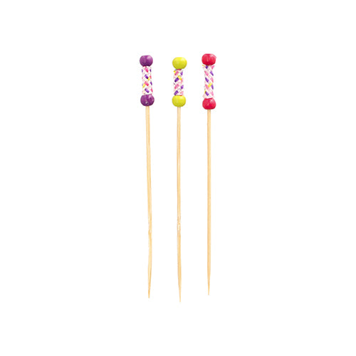 Three PAPSTAR 100 finger food picks from PAPSTAR GmbH made of bamboo stand upright. Each pick has a decorative handle with colorful beads (purple, yellow, pink) and a cross pattern.