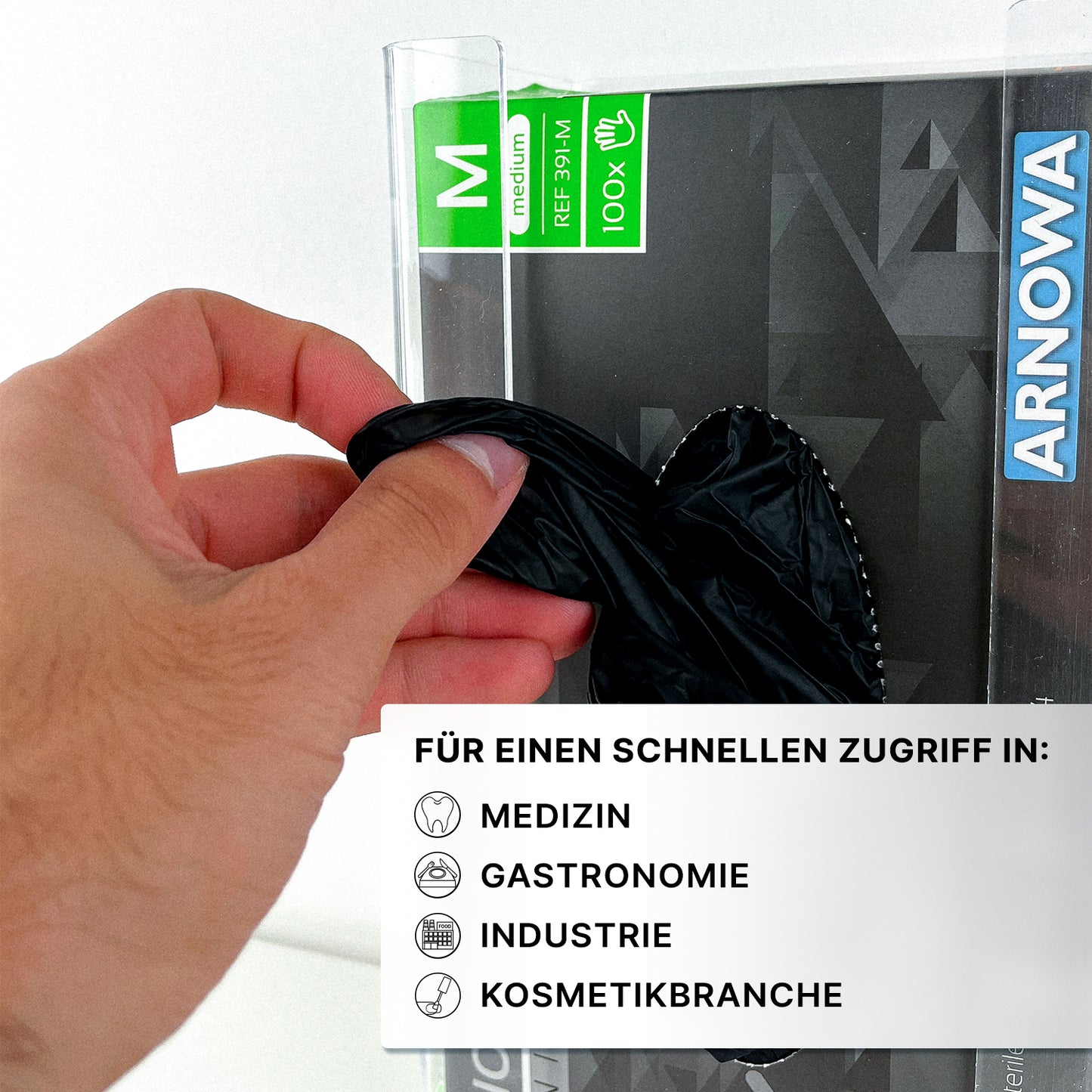 A hand pulls a black glove from the transparent ARNOMED glove dispenser for 3-fold filling from ARNOWA GmbH - ideal for storing disposable gloves in medicine, gastronomy, industry, and cosmetics.