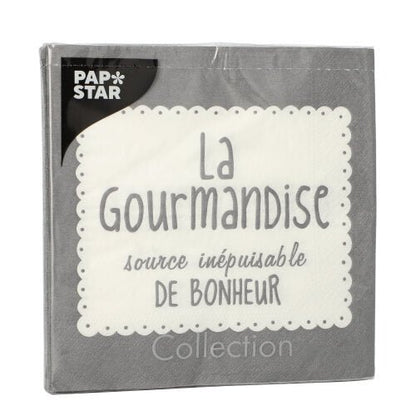 A gray PAPSTAR GmbH 20 napkin pack (33x33 cm, 3-ply, 1/4 fold) is adorned with a white lace border, the French text "La Gourmandise source inépuisable de bonheur" and the PAP*STAR logo in white on black in the top left corner.