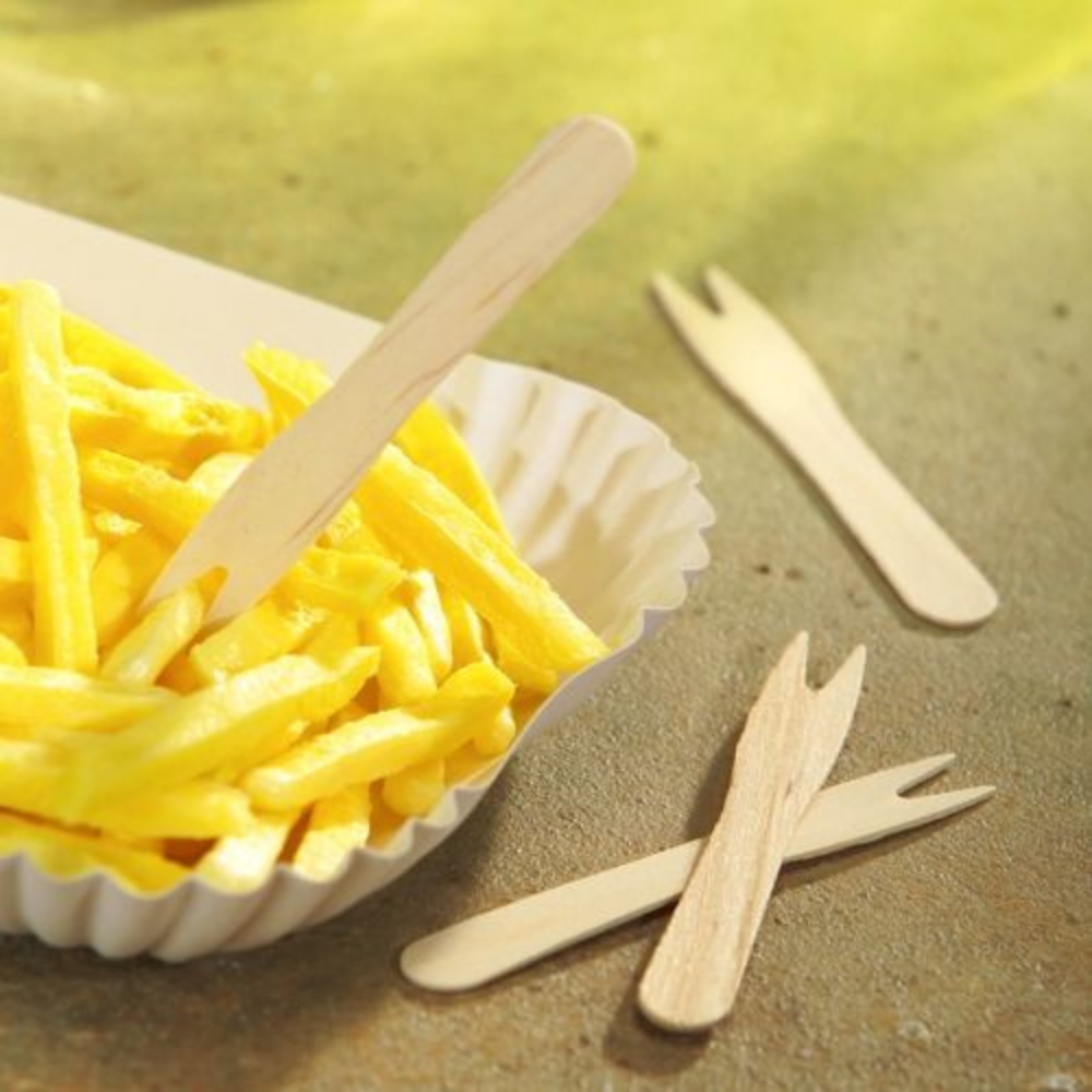A serving tray with golden-brown fries is accompanied by eco-friendly PAPSTAR "pure" birch wood forks from PAPSTAR GmbH. Two more PAPSTAR "pure" fry forks, wood 8.5 cm, are lying on the side. The scene is set against a light background with a warm, sunny hue.