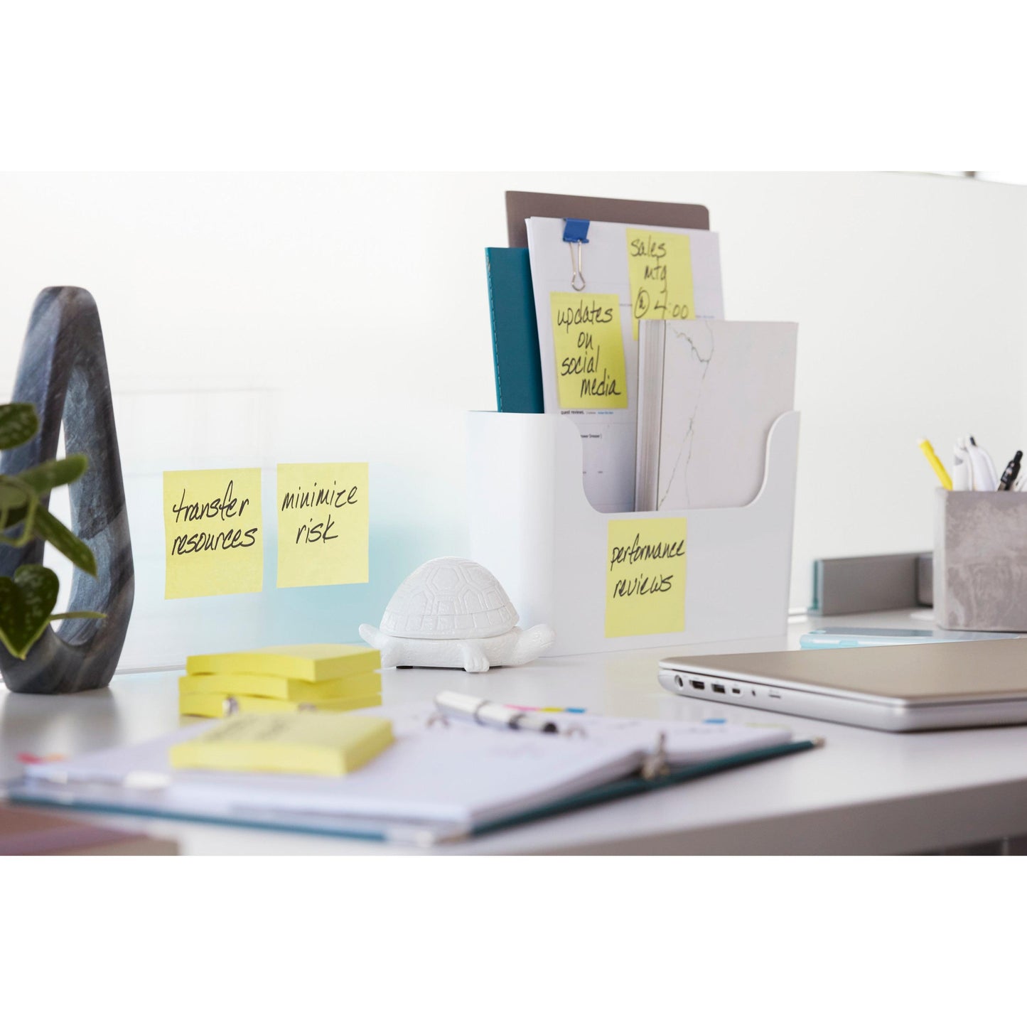 On a tidy office table with binders, supplies, a plant, and a small white turtle figure are 3M Deutschland GmbH Post-it® Super Sticky Notes (Yellow, 47.6 mm x 47.6 mm), ideal for reminders like "Transfer resources" and "Minimize risk".