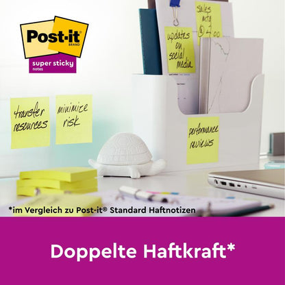 On a desk, there are 3M Post-it® Super Sticky Z-Notes in Yellow (76x127mm, 90 sheets, 12 blocks, PEFC-certified) on glass next to a white partition with office supplies, a turtle figure, and the inscription "Double the sticking power*".