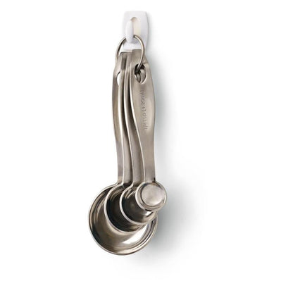 Four stainless steel measuring spoons on a metal ring hang on a 3M Deutschland GmbH Command™ Mini Hook, 17006 - securely attached without drilling and easy and residue-free to remove from the white wall.