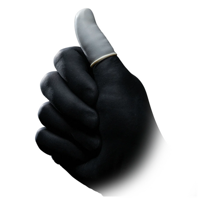 A person with black skin gives a thumbs-up gesture, presenting their white-painted thumb, adorned at the base with an AMPri MED-COMFORT Latex Finger Cot ring. The background is plain white.