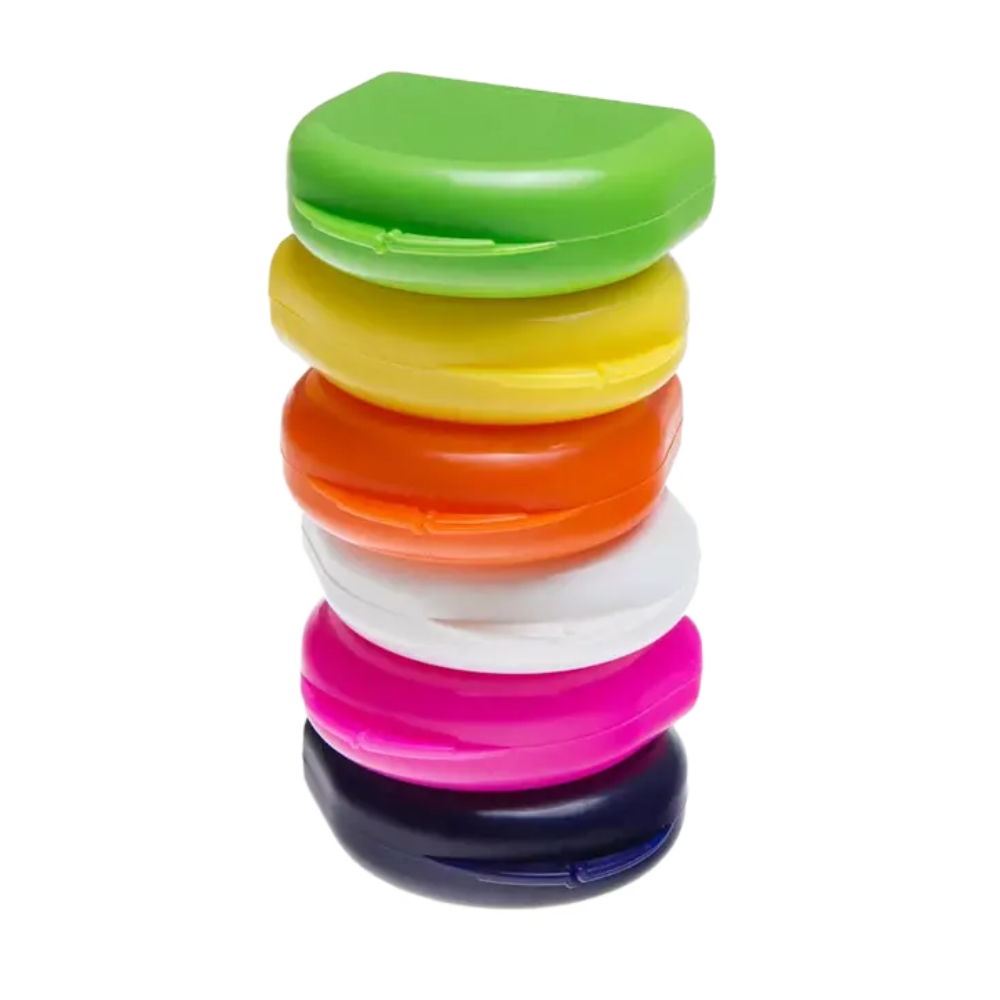 A vertical stack of six crescent-shaped AMPri PP Dental mouthguard boxes in bright colors: Green, Yellow, Orange, White, Pink, and Black. These containers, manufactured by AMPri Handelsgesellschaft mbH from durable polypropylene, are perfect for stylishly storing mouthguards against a flawlessly white background.