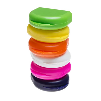A vertical stack of six crescent-shaped AMPri PP Dental mouthguard boxes in bright colors: Green, Yellow, Orange, White, Pink, and Black. These containers, manufactured by AMPri Handelsgesellschaft mbH from durable polypropylene, are perfect for stylishly storing mouthguards against a flawlessly white background.