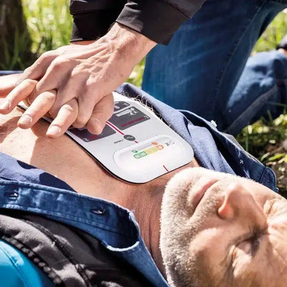 An adult man receives chest compressions with the innotas Beurer LifePad® resuscitation aid (discontinued item, 1 piece) while an AED pad is placed on his bare chest for effective first aid.