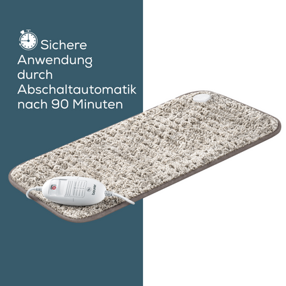 Pictured is a rectangular electric heating pad with a textured beige surface. A control device is connected to the pad via a cable. The German text on the left reads 'Safe use through automatic shut-off after 90 minutes' with a clock symbol above it. This product from Beurer GmbH, the Beurer HK 123 XXL Nordic heating pad, offers 3 heat settings and is available in XXL format, perfect for maximum coverage.