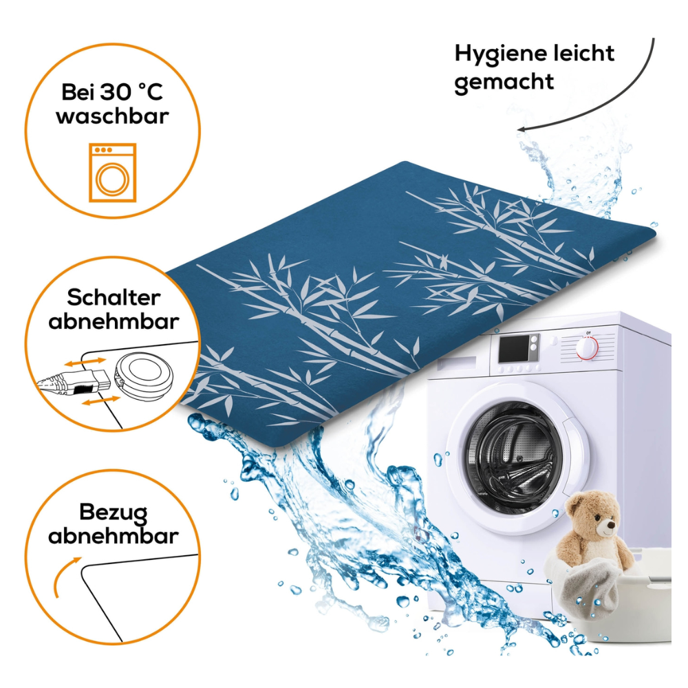 An image shows a washing machine and a blue mattress with a bamboo pattern. The text highlights features such as washable at 30°C, removable switch, quick heating, and removable cover. A teddy bear sits next to the washing machine, and water splashes around the products, all certified according to OEKO-TEX® STANDARD 100. The Beurer HK 35 heating pad | Pack (1 piece) of the Beurer GmbH is prominently featured in the scene.