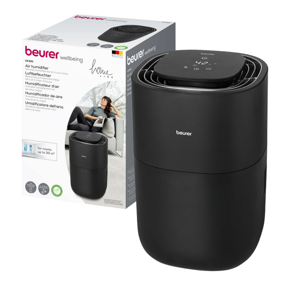 A black Beurer LB 200 humidifier from Beurer GmbH is placed next to its packaging box, which features, besides the brand name, a picture of the humidifier and a multilingual text stating that it is suitable for rooms up to 20 square meters. A woman is visible in the picture on the box.