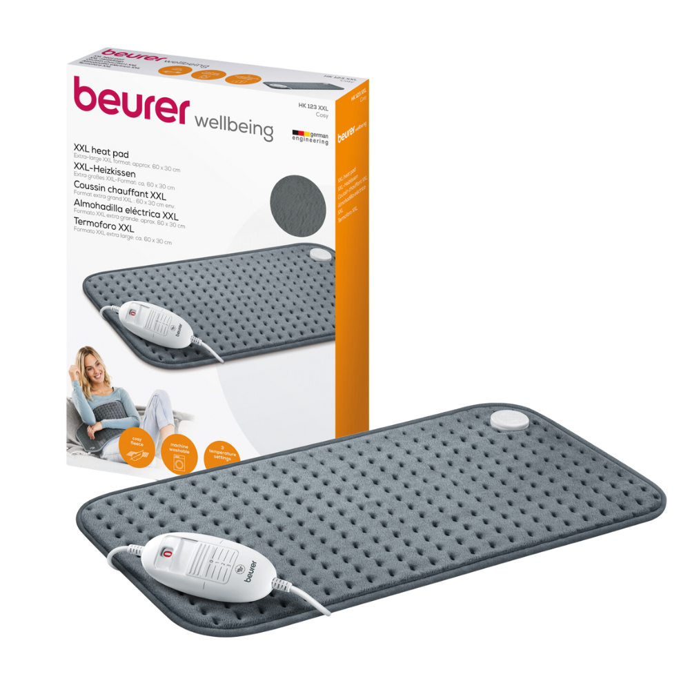 A rectangular, gray Beurer HK 123 XXL Nordic heating pad from Beurer GmbH with packaging. The heating pad has a soft, textured surface and an attached controller with 3 heat settings. The packaging shows an image of a woman using the heating pad and lists product specifications in multiple languages.