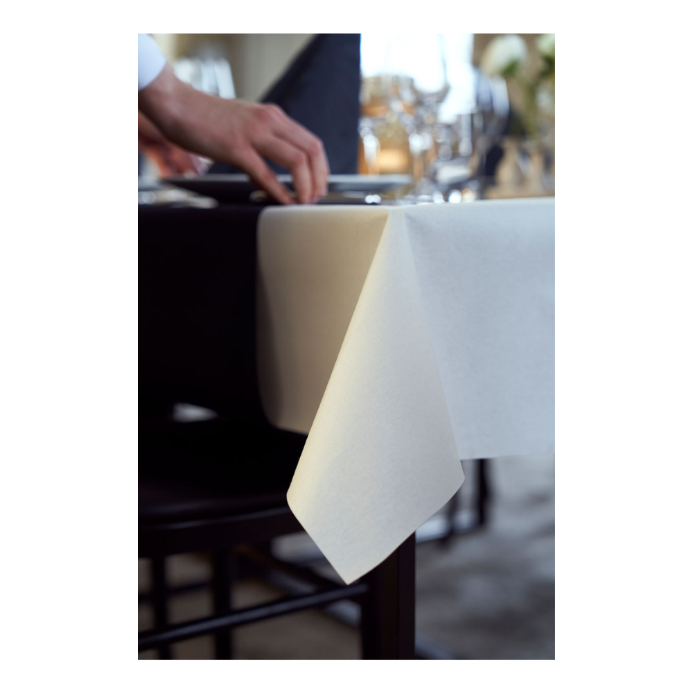 A person arranges a neatly folded Duni Dunicel tablecloth from Duni GmbH on a table set with glassware and a folded black napkin, suggesting an upscale table setting.