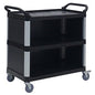 A black Novocal multipurpose cart made of plastic with three enclosed plastic shelves, silver columns, raised handles at both ends, and four swivel casters. The empty cart is photographed against a white background.