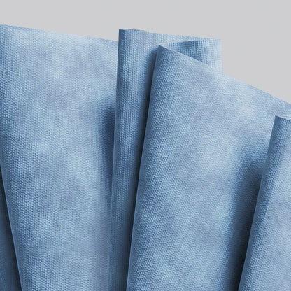 Several blue WypAll® X90 PowerClean napkins from Kimberly-Clark GmbH out of the 1 roll x 450 sheets jumbo roll are arranged overlapping against a solid light background.