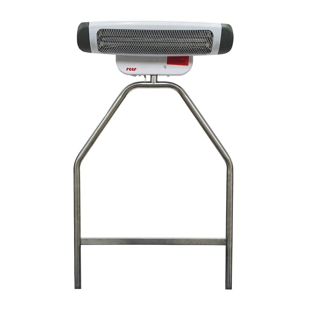 On the Novocal stainless steel bracket for radiant heaters, there is a white-gray electric heater with a metal grid cover and a red "reer" logo mounted, which is ideal as an accessory in the changing area for secure attachment to a changing trolley.
