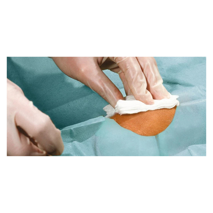 A close-up of gloved hands cleaning a small skin area with a white cloth, surrounded by blue-green Hartmann Foliodrape® Protect self-adhesive, sterile, individually packaged drapes of Paul Hartmann AG.