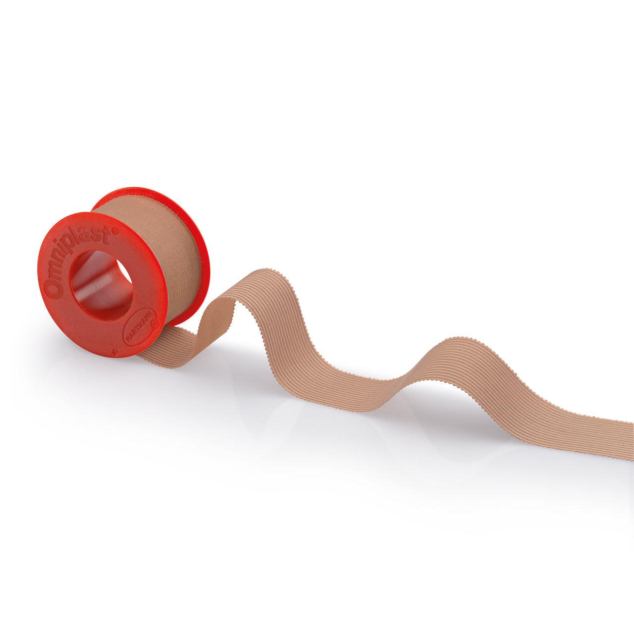 A roll of beige Hartmann Omniplast® spool plaster with a red dispenser labeled "Paul Hartmann AG" on a white background. The tape runs in a wavy pattern to the right side of the dispenser.