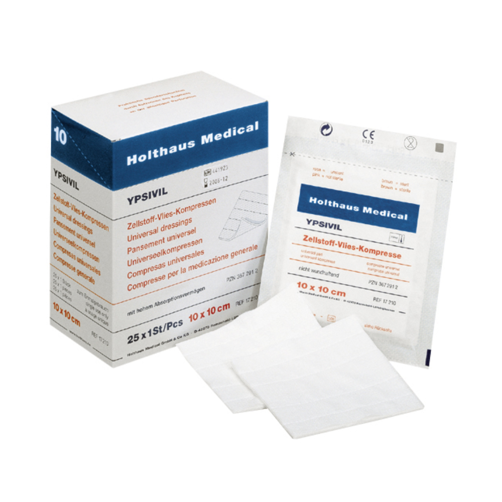 A box of Holthaus Ypsivil cellulose fleece compress, 10 x 10 cm from Holthaus Medical GmbH & Co. KG stands next to a single, unopened package of the same bandage. In front of it lie two unfolded square bandages, whose size and material properties are clearly recognizable.