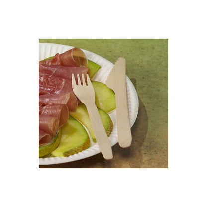 A PAPSTAR "pure" disposable wooden fork and the PAPSTAR "pure" wooden knife 16.5 cm from PAPSTAR GmbH are elegantly placed on a white paper plate, topped with thin slices of sausage and green apple. The eco-friendly ensemble rests gracefully on a green surface.