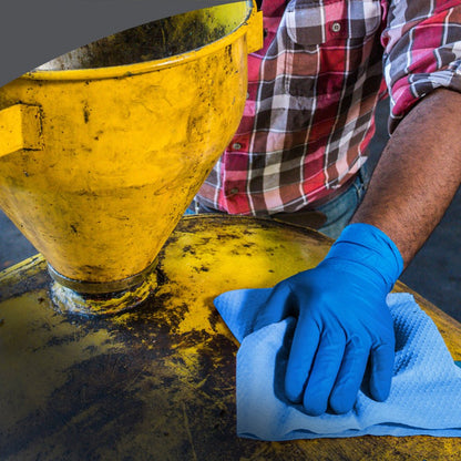 A person in a red plaid shirt wipes a large yellow industrial tank with Kimberly-Clark GmbH WypAll® X80 PowerClean - BRAG™ Box / Steel Blue cloths and a blue glove, emphasizing professional industrial cleaning.