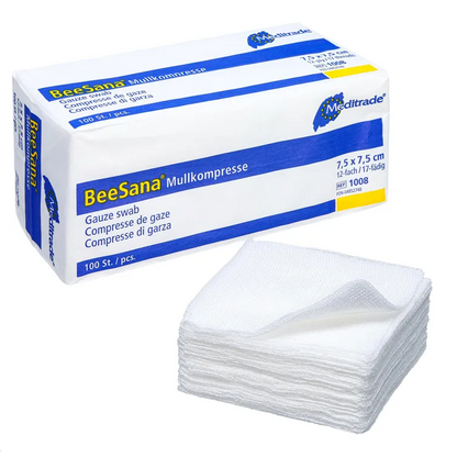 The image shows a box labeled “Meditrade BeeSana® gauze compress, non-sterile” next to a stack of white gauze compresses, ideal for effective wound care. The box measures 7.5 x 7.5 cm and contains 100 pieces. These gauze compresses are neatly stacked in front of the box, manufactured by Meditrade GmbH.
