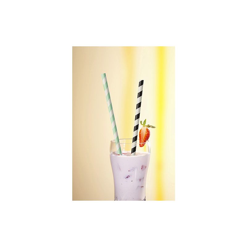 A glass of purple milkshake with ice, topped with a strawberry and two straws from PAPSTAR 100 paper straws Ø 6 mm - one green-white striped, one black-white - from PAPSTAR GmbH, against a softly lit yellow background.