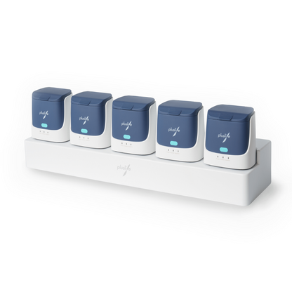 A white base holds five identical rectangular devices with blue tops. The devices are arranged in a row and each has a logo on the front with the inscription 'Plaqless'. The base with the matching logo serves as a Pluslife 5 Ports HUB for Pluslife POC-NAT test devices | Pack (1 piece) and likely functions as both a charging station and an organizer.
