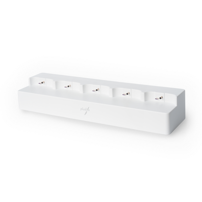 A white, rectangular charging station with six individual slots, each equipped with a connector pin for charging compatible devices. The surface of the station is smooth with a slightly raised back, and the front features the 'Pluslife' logo printed in gray. Ideal for use as a Pluslife 5 Ports HUB for Pluslife POC-NAT test devices | Pack (1 piece).