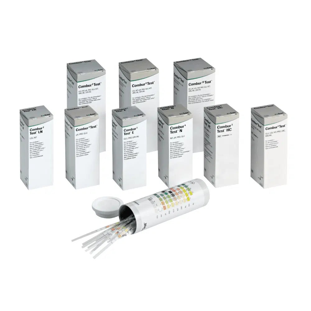 Behind an open cylindrical container with a lid are hidden nine boxes labeled "Combur®" by Servoprax GmbH, each containing 100 Roche urine test strips. On the side of the container is a multicolored chart, which is perfect for conducting a quick test.