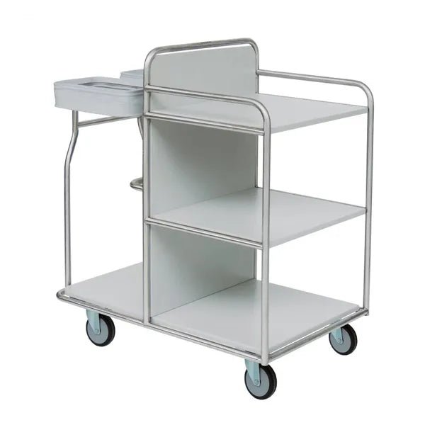 The Novocal station trolley has three shelves, four wheels, a handle, and a small side compartment at the top left. It is made of sturdy stainless steel with fully welded round tube connections and is depicted empty on a white background.