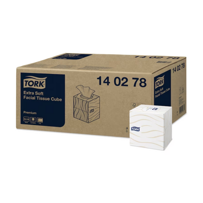 Next to a small dispenser cube with tissues is a large box labeled "Tork 140278 Tork extra soft cosmetic tissues in dispenser cube." Both are adorned with the Tork logo, emphasizing their status as high-quality cosmetic tissues from TORK – Essity Professional Hygiene Germany GmbH.