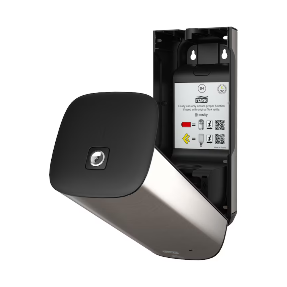 The Tork 460009 Skincare Dispenser from TORK – Essity Professional Hygiene Germany GmbH is openly presented and features a stylish, modern design with a metallic surface and a black front panel. Inside, operating instructions and QR codes are visible. This wall-mounted stainless steel dispenser is designed for efficient towel use and features innovative Intuition Sensor technology.