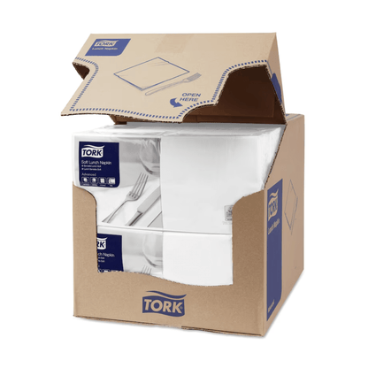 A box of Tork 477414 Soft Lunch Napkins White Advanced 3-ply is partially open, revealing four stacks of three-ply, industrially compostable white napkins. The box features the blue-and-white branding of TORK – Essity Professional Hygiene Germany GmbH – along with product information and a clear “Open here” instruction on the top flap.